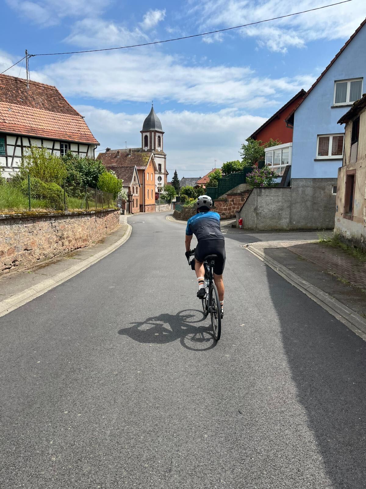 Cyclist rolling through an Alsatian village toward the church steeple