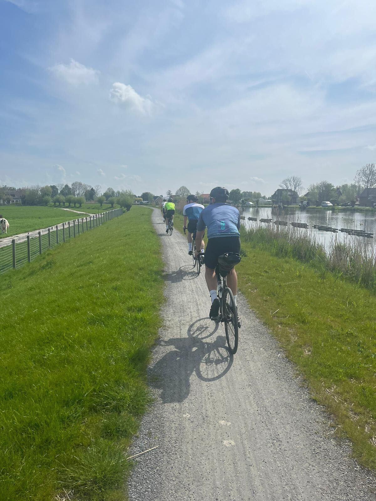 Cyclists riding along a dyke path beside a Dutch waterway
