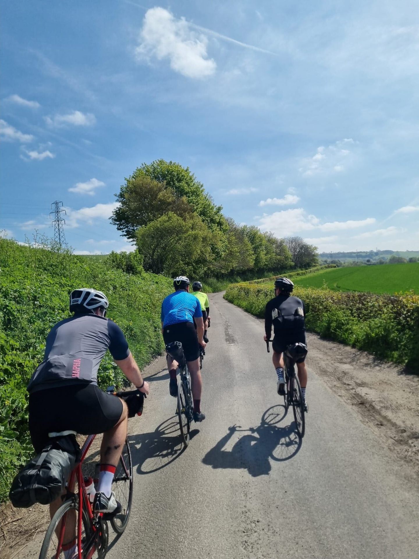 Group of four cyclists climbing a quiet country road