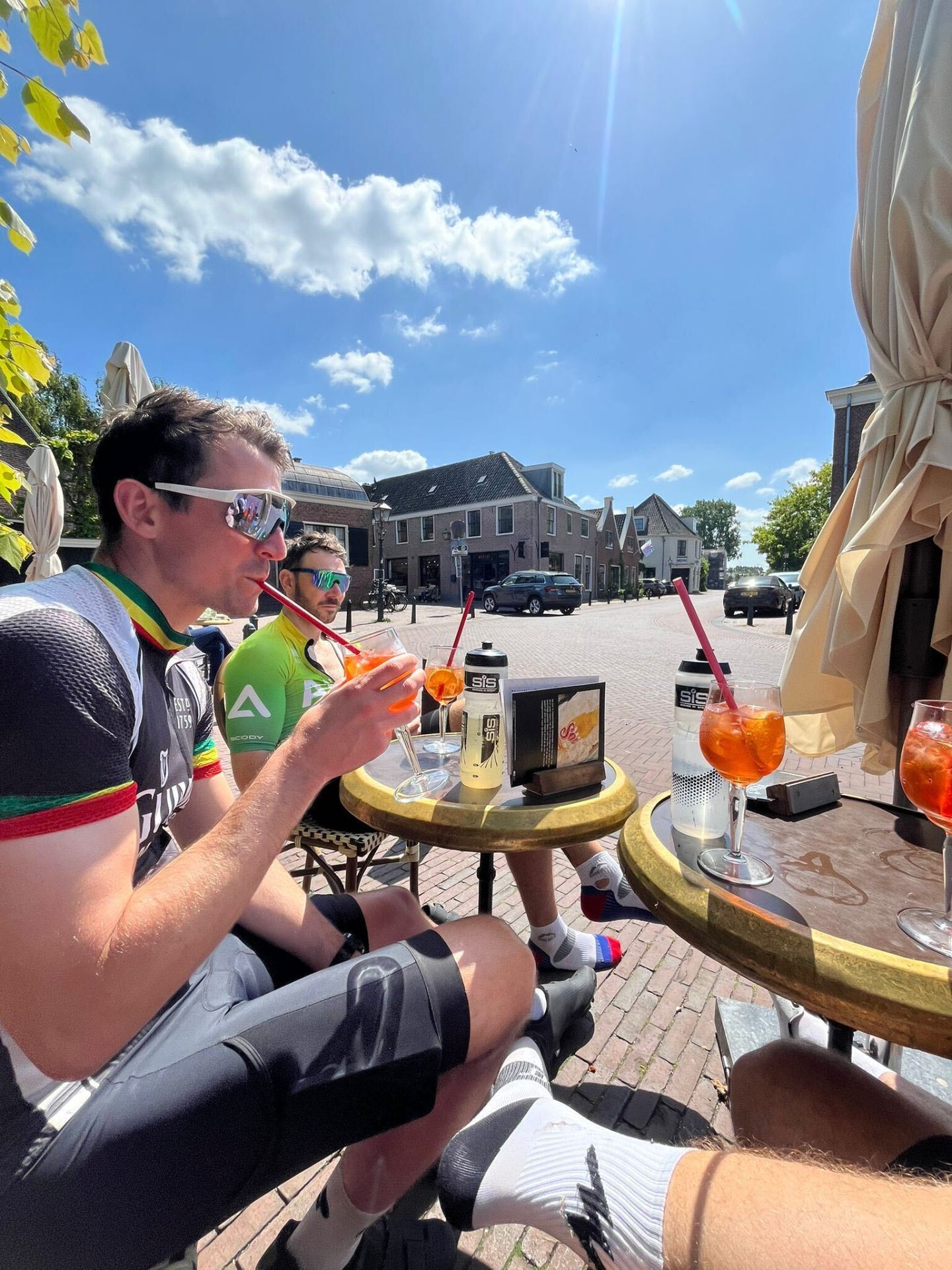 Cyclists enjoying Aperol spritzes at a Dutch village square cafe