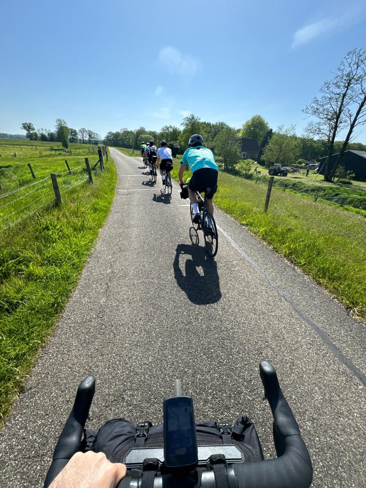 Riders on a narrow farm lane past green pastures