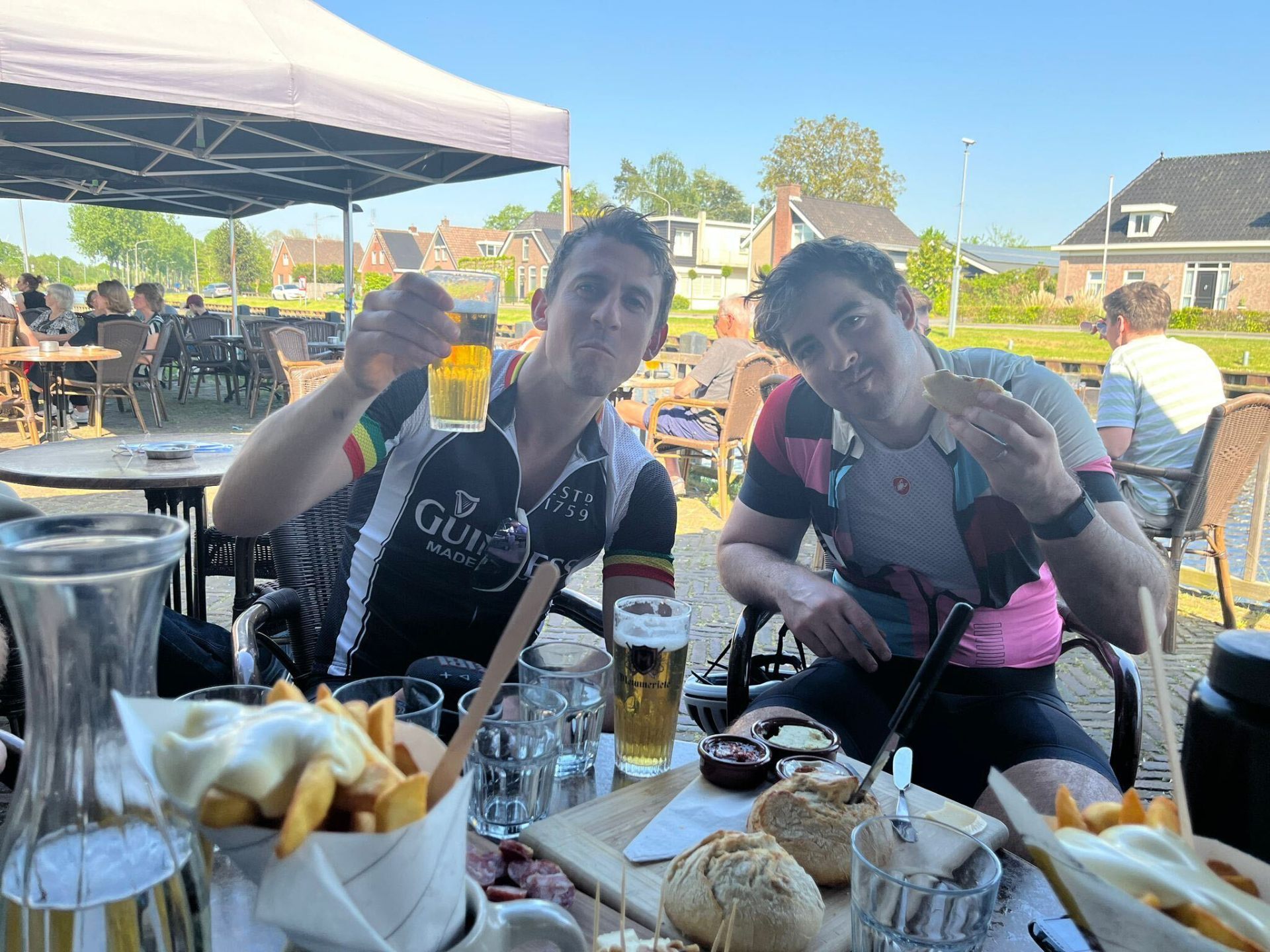 Riders enjoying beers and frites at a canal-side terrace